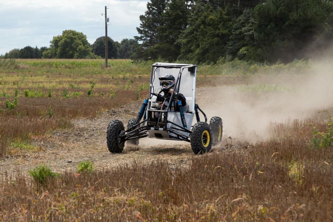 A Kettering student is driving an off-road vehicle, testing it in preparation for the Baja SAE competition